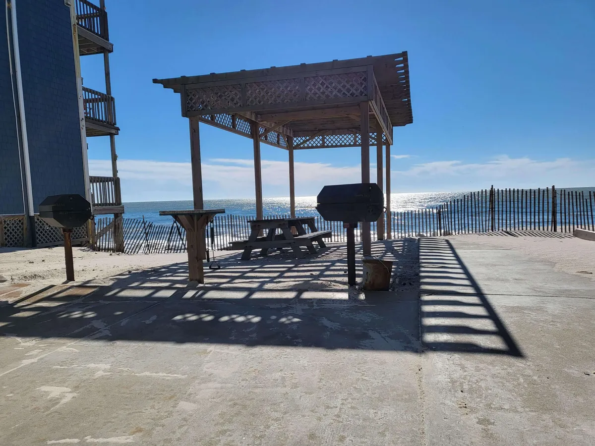 A cozy grilling area with a picnic table overlooks the ocean, set up for a relaxed meal or sunset barbecue. The setting feels inviting and intimate, perfect for couples looking to create memorable shared experiences.