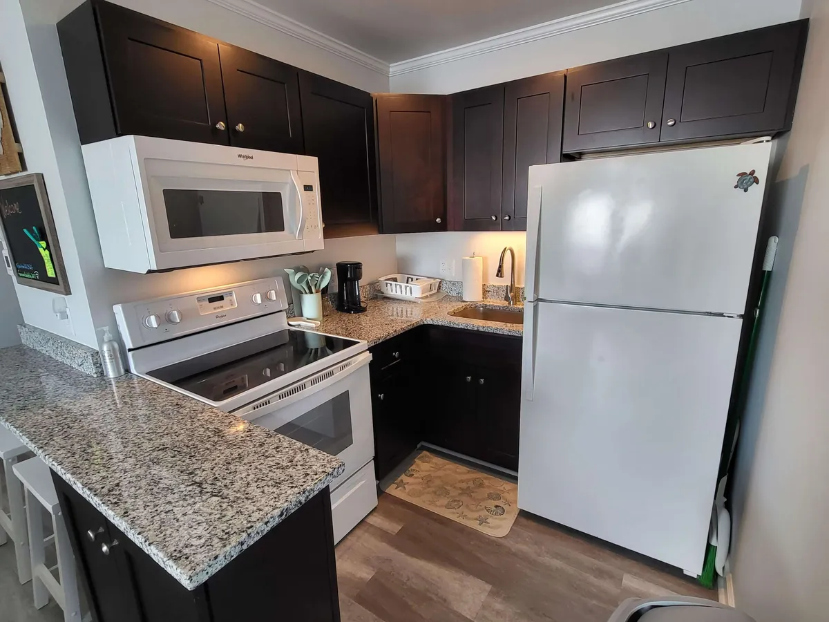 This image captures a modern kitchen interior featuring granite countertops, stainless steel appliances, and dark wooden cabinets. The space is well-lit and organized, creating a welcoming environment ideal for cooking and socializing.